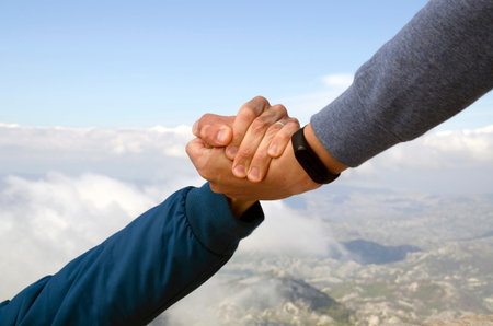 Friends hold hands over the cliff. Friendship, mutual help, trust, salvation, hope.