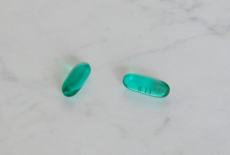Two green pills close-up on a white table. Vitamins, supplements, antibiotics, medications, emergency care, painkillers.の写真素材