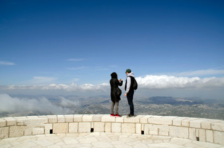 young couple standing on top of the mountain and looking at the viewの写真素材