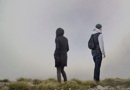 Young couple standing in the fog on the top of a mountain.の写真素材