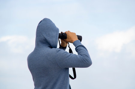 Male photographer taking picture with camera on blue sky background.の写真素材