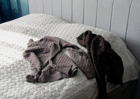 Warm knitted woolen sweaters lie on the bed.