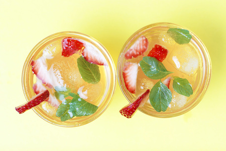 A Cold summer drink with ice and strawberries on a yellow background, top viewの写真素材