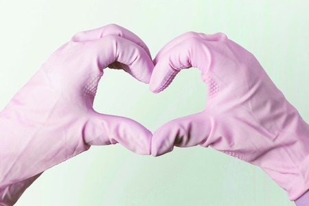 A Hands in rubber gloves in the shape of a heart on a white backgroundの写真素材
