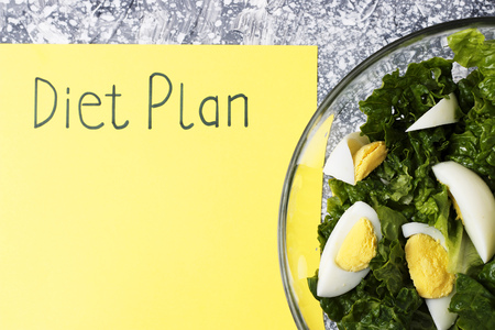 An Inscription Diet plan on yellow sheet and salad. View from aboveの写真素材