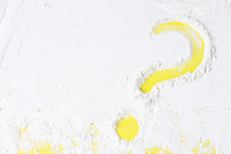 A question mark drawn on flour, a yellow background, copy spaceの写真素材