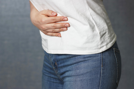 A girl holding her belly, side view, concept of acute painの写真素材