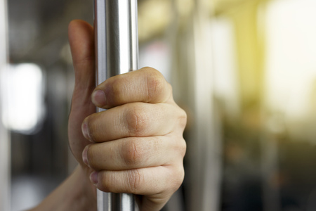 Man's hand holding a railing on a bus close upの写真素材