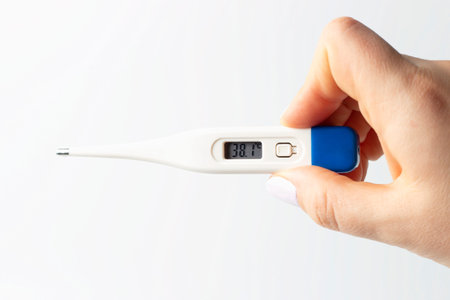 Female hand holds a thermometer to measure temperature on a white background.
