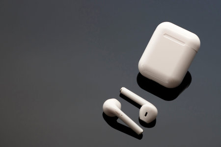 Wireless white headphones and case on black background with copy space, top view