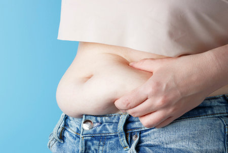 A woman's hand holding excessive belly fat, the concept of weight loss