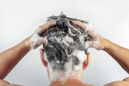 Men's hands wash their hair with shampoo and foam on a white background, rear view