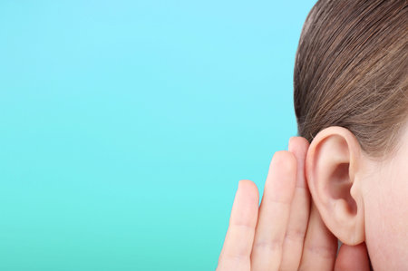 The girl listens attentively with her palm to her ear close up, the news concept