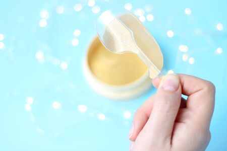 Female hand holds transparent patches on a blue background with bokeh top viewの写真素材