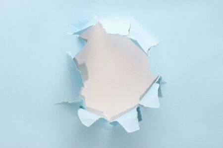 Torn blue paper with a white hole inside, copy space.の写真素材