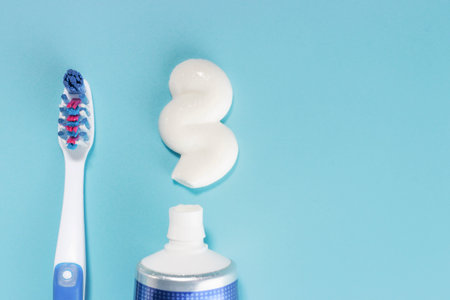 Toothbrush and squeezed toothpaste on a blue background with copy space.