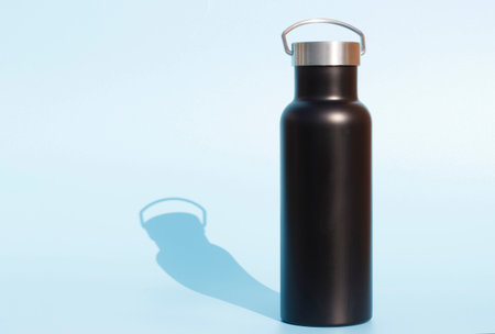 A black reusable bottle for water on a blue background