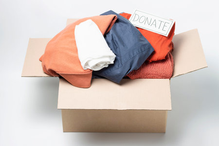 Clothes in a cardboard box and the inscription Donate on a white background