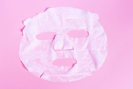 White fabric mask on a pink background close-up, skin hydration concept.の写真素材