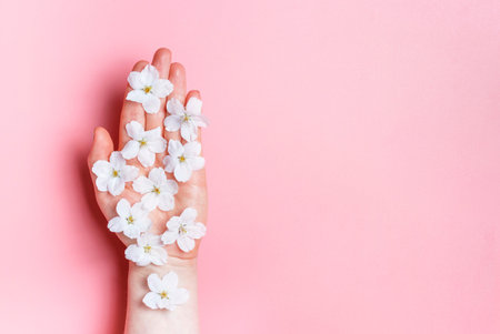 Flowers on female hand, a pink background, copy space, natural care conceptの写真素材