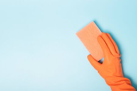 A woman's hand in an orange glove holds a blue rag, a copy of space, the concept of spring cleaningの写真素材