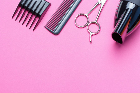 A set of tools for the hairdresser, hairdryer, scissors, comb, on a pink background, a copy of the...