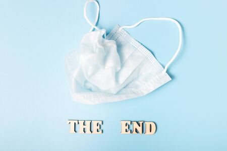 Crumpled mask and inscription, the end of the coronavirus, on a blue background, the concept of the end of the coronavirusの写真素材