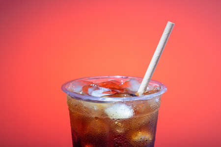 Ice coffee in a plastic glass with a straw on a pink background, copy of the spaceの写真素材