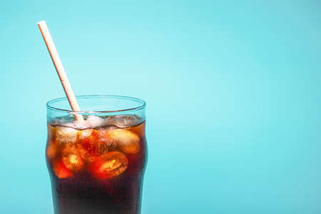 Coffee with ice in a glass cup with a tube on a blue background, a copy of the spaceの写真素材