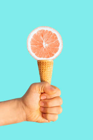Male hand holds a ice cream cone with orange, a creative summer background.の写真素材