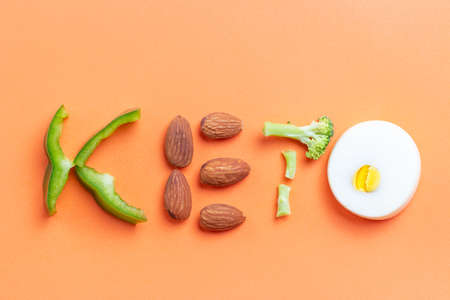 Inscription keto laid out of pepper, broccoli, eggs and almonds, on an orange backgroundの写真素材