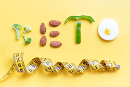 Inscription keto composed of vegetables and measuring tape on a yellow backgroundの写真素材