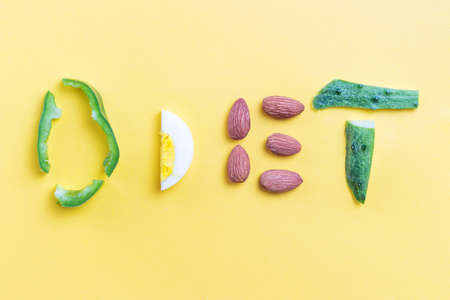 Inscription diet made of pepper, almond, broccoli, eggs and cucumber on a yellow backgroundの写真素材