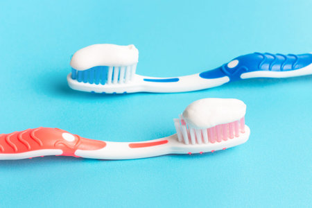 Blue and a pink toothbrush with toothpaste on a blue background