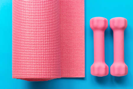 Gymnastic mat and sports dumbbells on a blue background, view from aboveの写真素材