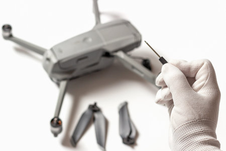 Quadruplicate and hand in a white glove with a screwdriver, Drone repair concept.