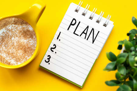 To-do list recorded in a notebook and a flower on a yellow backgroundの写真素材