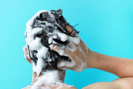 A man washes his head with shampoo on a blue background, a copy of the spaceの写真素材