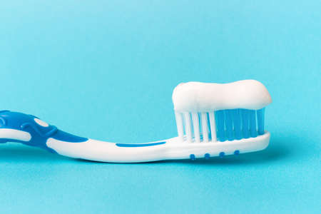 Blue toothbrush with toothpaste on a blue background with copy spaceの写真素材