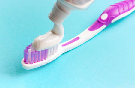Squeezed out toothpaste on a toothbrush on blue background close-up.の写真素材