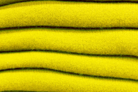 Stack of warm sweaters in trendy green sheen color close up