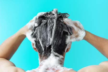 A man washes his head with shampoo on  blueの写真素材