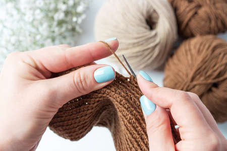 Womens hands are crocheting on background of skeins of yarn.の写真素材