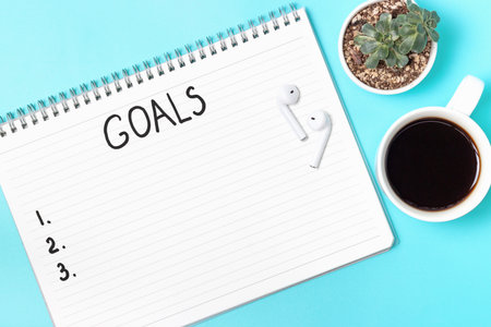 The inscription goals in a notebook on blue background top view.