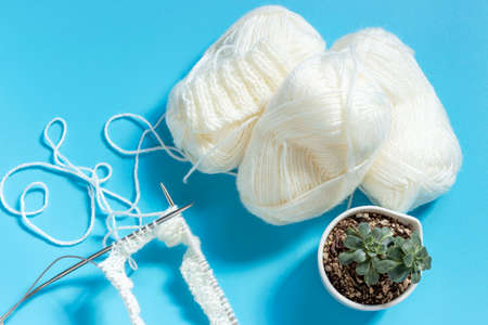 White yarn and knitting needles on blue background top view.の写真素材