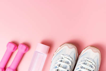 Sneakers, dumbbells on pink background top view, copy spaceの写真素材