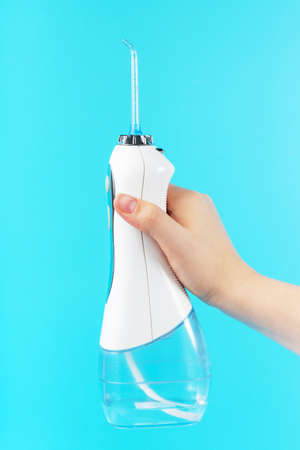 Woman's hand holds a dental irrigator on a blue background.の写真素材