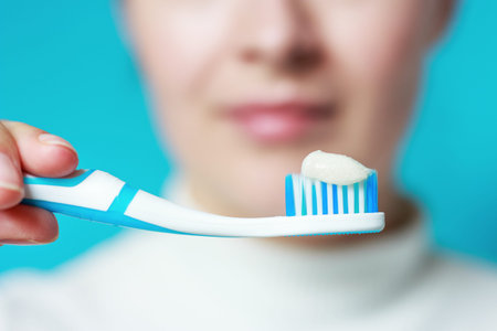 Girl holding a toothbrush with toothpaste on blue background, selective focus.
