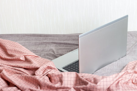 Modern laptop in bed close-up, concept of work at homeの写真素材