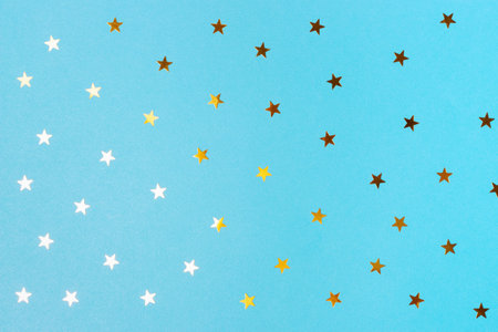 Golden confetti in shape of star on blue background, texture and background.の写真素材